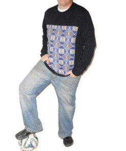 Man wearing black sweater with blue geometric African wax panel on the chest.