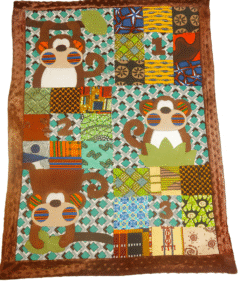 Baby blanket with African wax patchwork, monkey appliqués, and brown minky fleece backing.