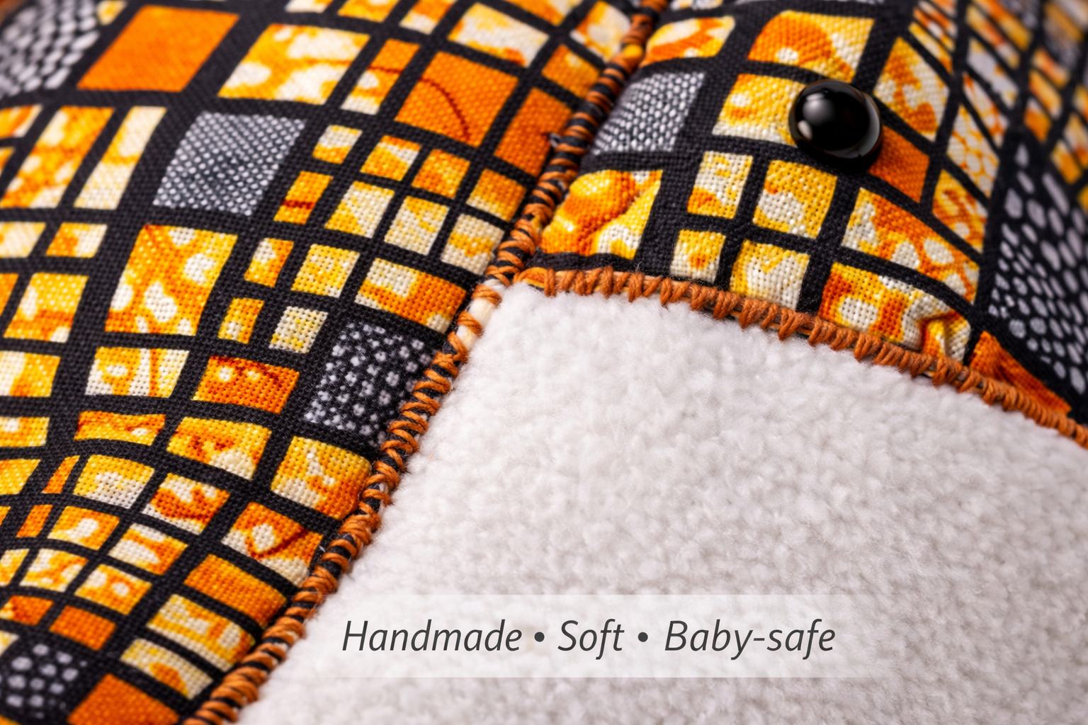 Close-up of African wax print fabric and stitching on handmade baby outfit and bib – soft baby-safe materials by AfriBloom