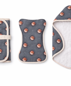 Flat lay of AfriBloom newborn care essentials including hooded baby towel, foldable changing mat and burp cloth in coordinated wax fabric