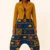 African woman wearing AfriBloom baggy harem pants with deep drop crotch, front view. Harem pants in African wax print styled with mustard jacket.