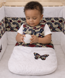 African print newborn crib set with handmade crib bumper, sleeping bag and organizer, baby sitting safely in crib
