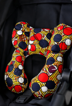 AfriBloom newborn support pillow placed in a car seat, showing ergonomic shape and soft African wax fabric