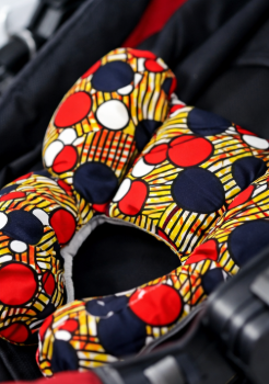 Close-up of AfriBloom newborn support pillow in a car seat, showing African wax fabric and soft padding for baby comfort