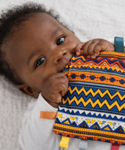 Baby holding AfriBloom crinkle sensory toy made with African wax fabric, colorful ribbon tags and soft texture