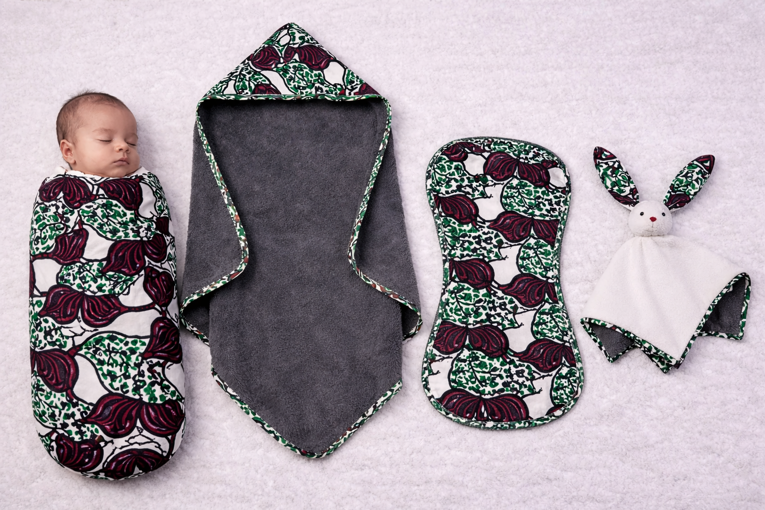 Newborn baby using African print swaddle and essentials bundle handmade in Belgium African print newborn essentials bundle including swaddle hooded towel burp cloth and animal blanky