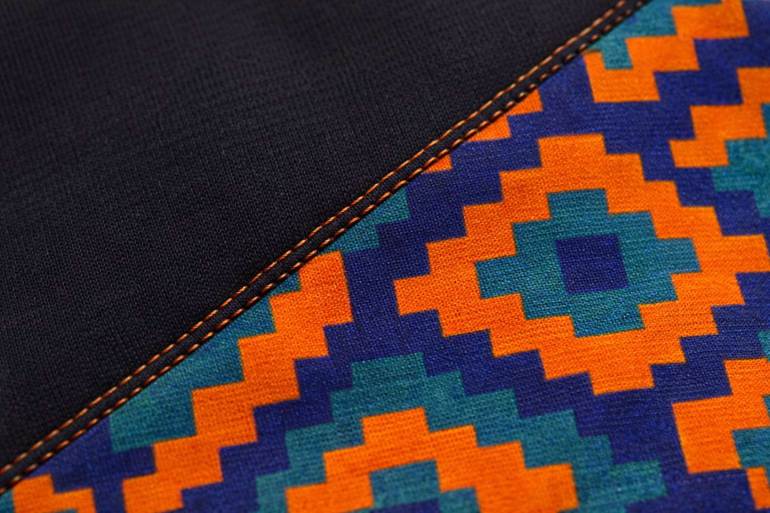 Close-up of African print diagonal panel with premium stitching on women’s black sweatshirt