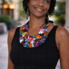 Woman wearing colorful handmade African statement necklace with wax print fabric buttons on black dress
