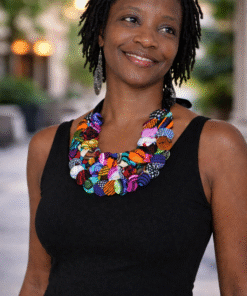 Woman wearing colorful handmade African statement necklace with wax print fabric buttons on black dress